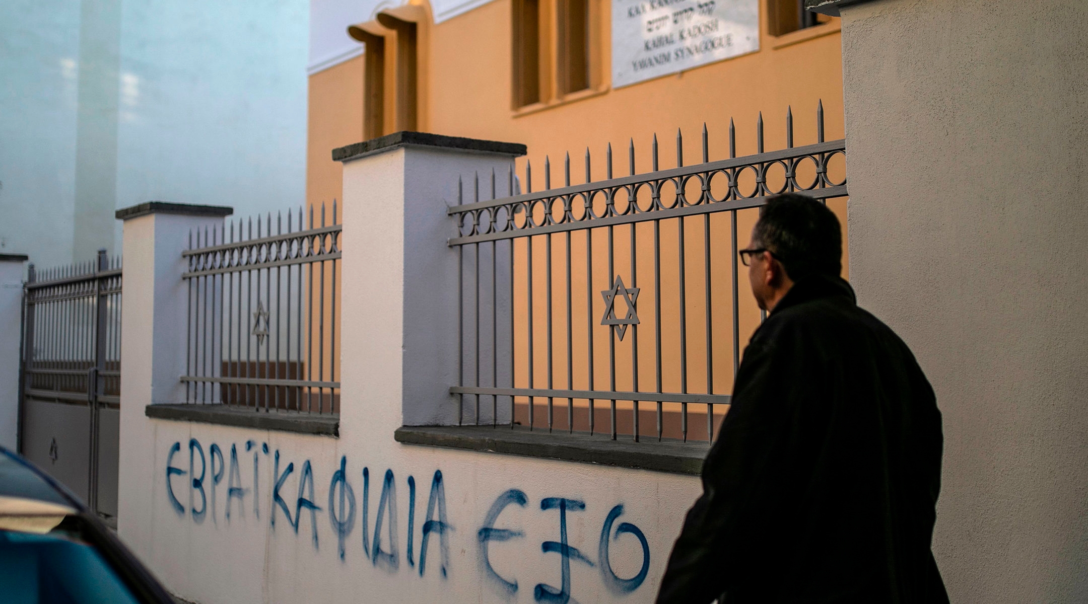 A man walking past a slogan reading "Outside the Jewish Snakes" on the fence of the synagogue of Trikala, Greece on December 31, 2019.(Lefteris Partsalis/AFP via Getty Images)