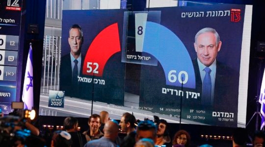 A TV screen broadcasts the exit poll results of the Israeli election in Tel Aviv on March 2, 2020. After more than a year of political deadlock, Benjamin Netanyahu and Benny Gantz have agreed to form a government together. (Menahem Kahana/AFP via Getty Images)