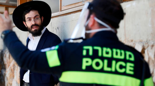 Israeli police officer speaking to a haredi student in Bnei Brak, Israel on April 2, 2020. (Jack Guez/AFP/Getty Images)
