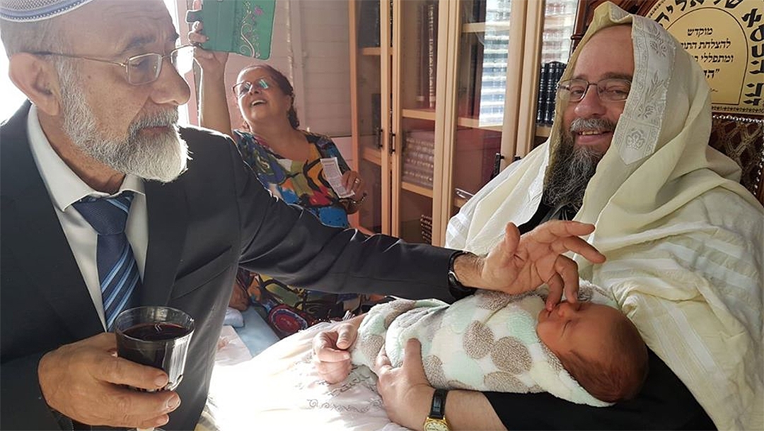 Rabbi Avraham Yeshayahu, right, Heber holding the son of a kidney donor during his Brith Milah in Jerusalem, Israel on Oct. 14, 2018. (Courtesy of Matnat Chaim)