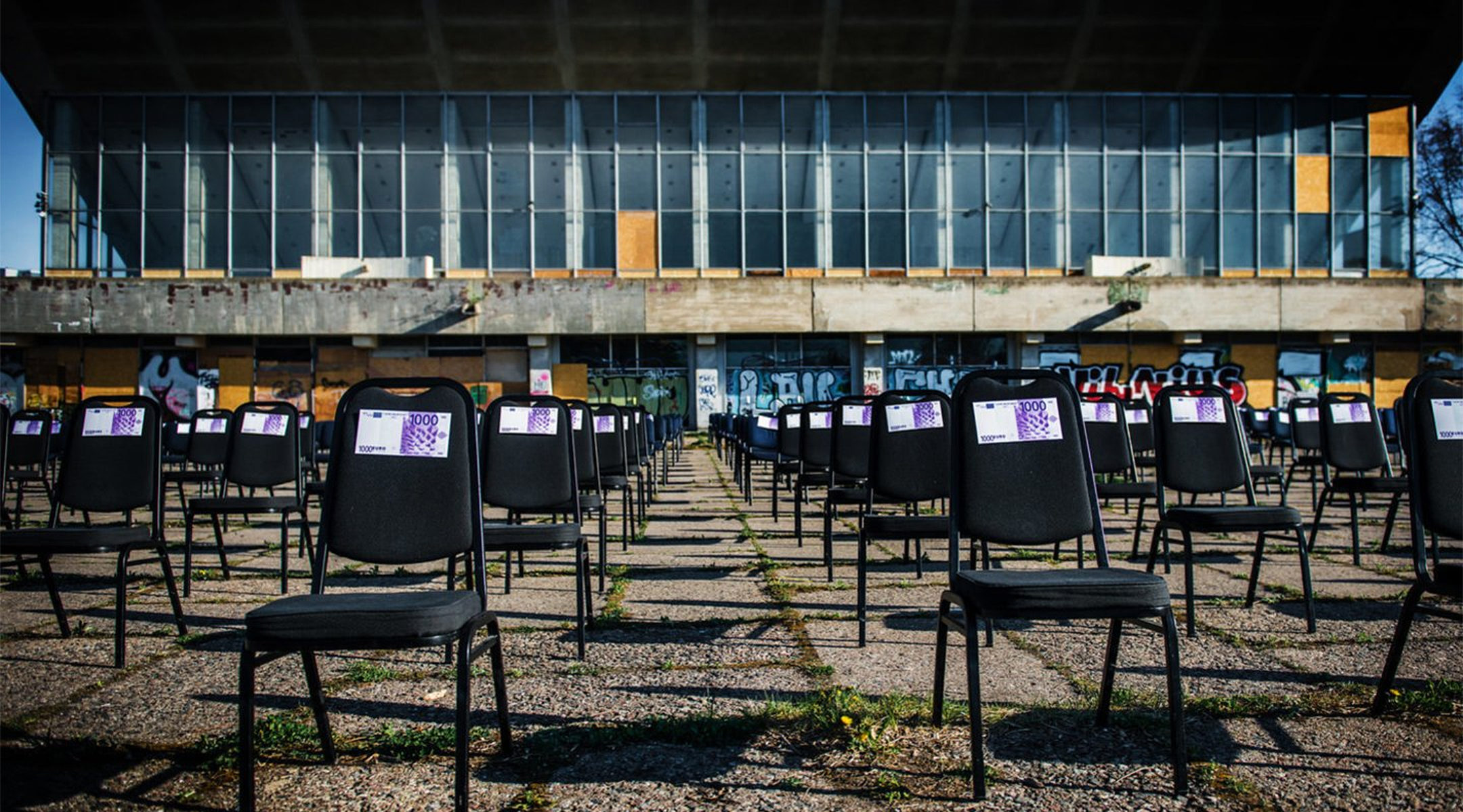 Chairs with fake money notes standing next to the decaying Palace of Concerts and Sports of Vilnius, Lithuania on May 1, 2020. (Courtesy of the display's organizers)
