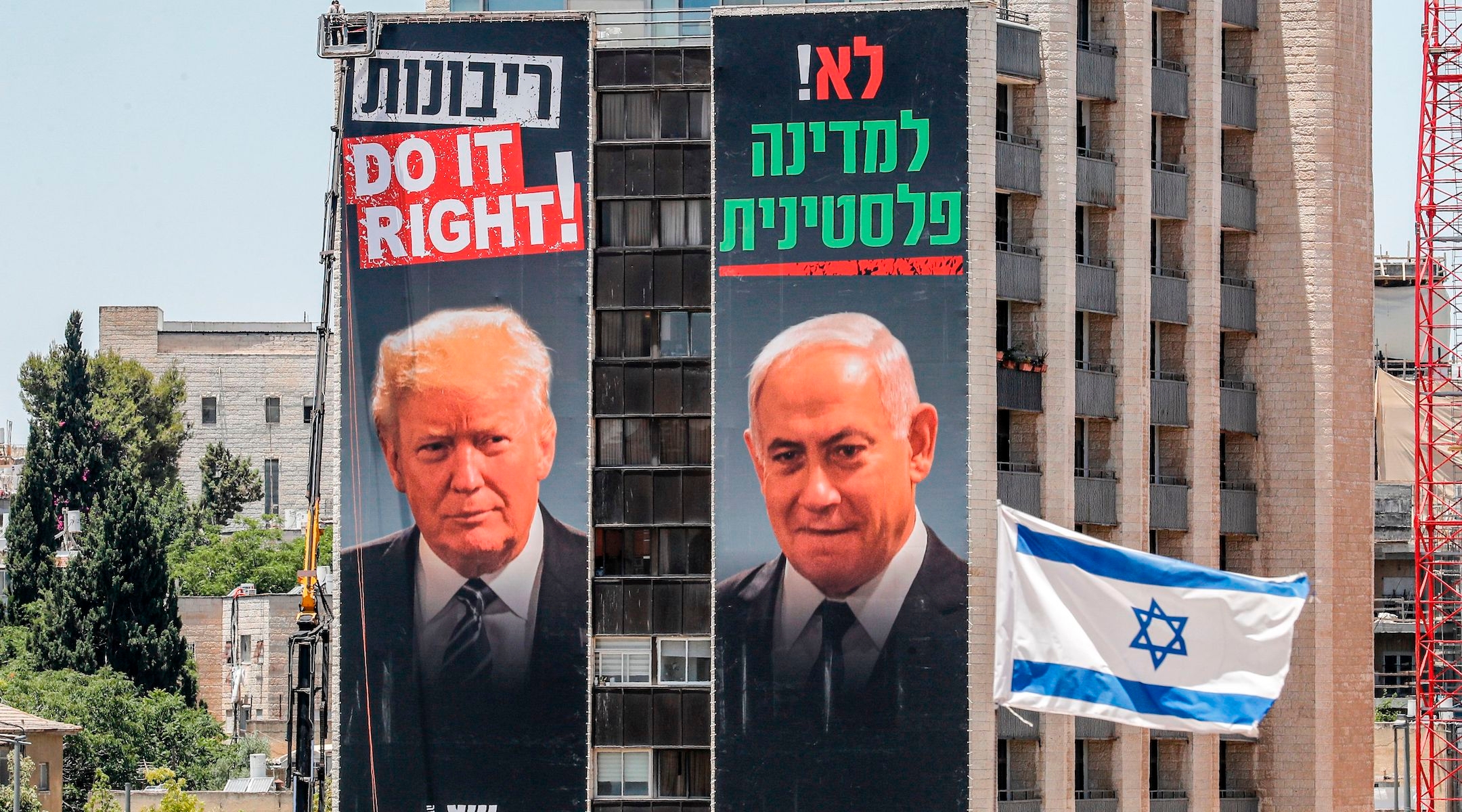 Giant posters on buildings in Jerusalem feature photos of Israeli Prime Minister Benjamin Netanyahu (right) and President Donald Trump, beneath slogans supporting West Bank annexation and opposing a Palestinian state. They were hung by the Yesha Council, an umbrella organization of Israeli settlements in the West Bank, which is split on Netanyahu's annexation plan. (Ahmad Gharbali/AFP via Getty Images)