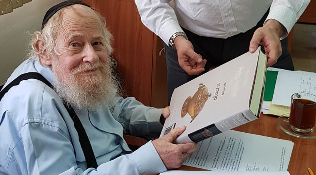 Rabbi Adin Even-Israel (Steinsaltz) inspects at his Jerusalem home an English-language translation of the Talmud based on his annotations on June 4, 2018. (Wikimedia Commons/SoInkleined)