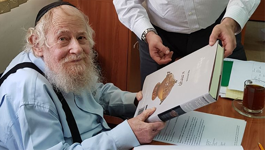 Rabbi Adin Even-Israel (Steinsaltz) inspects at his Jerusalem home an English-language translation of the Talmud based on his annotations on June 4, 2018. (Wikimedia Commons/SoInkleined)