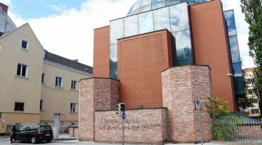 A man walks past the defaced facade of the synagogue of Graz, austria on Aug. 19, 2020. (Christian Jauschowetz)