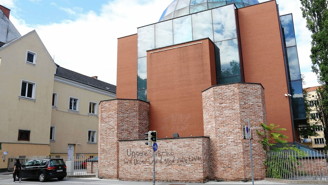 A man walks past the defaced facade of the synagogue of Graz, austria on Aug. 19, 2020. (Christian Jauschowetz)