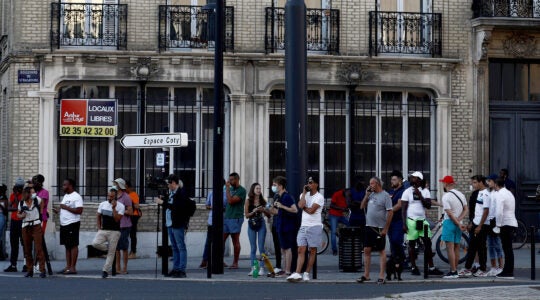 Pedestrians watch police outside a bank in Le Havre, France, where a hijacker has taken several hostages demanding the freedom of Palestinians in Israel on Aug. 7, 2020. (Sameer Al-Doumy/AFP via Getty Images)