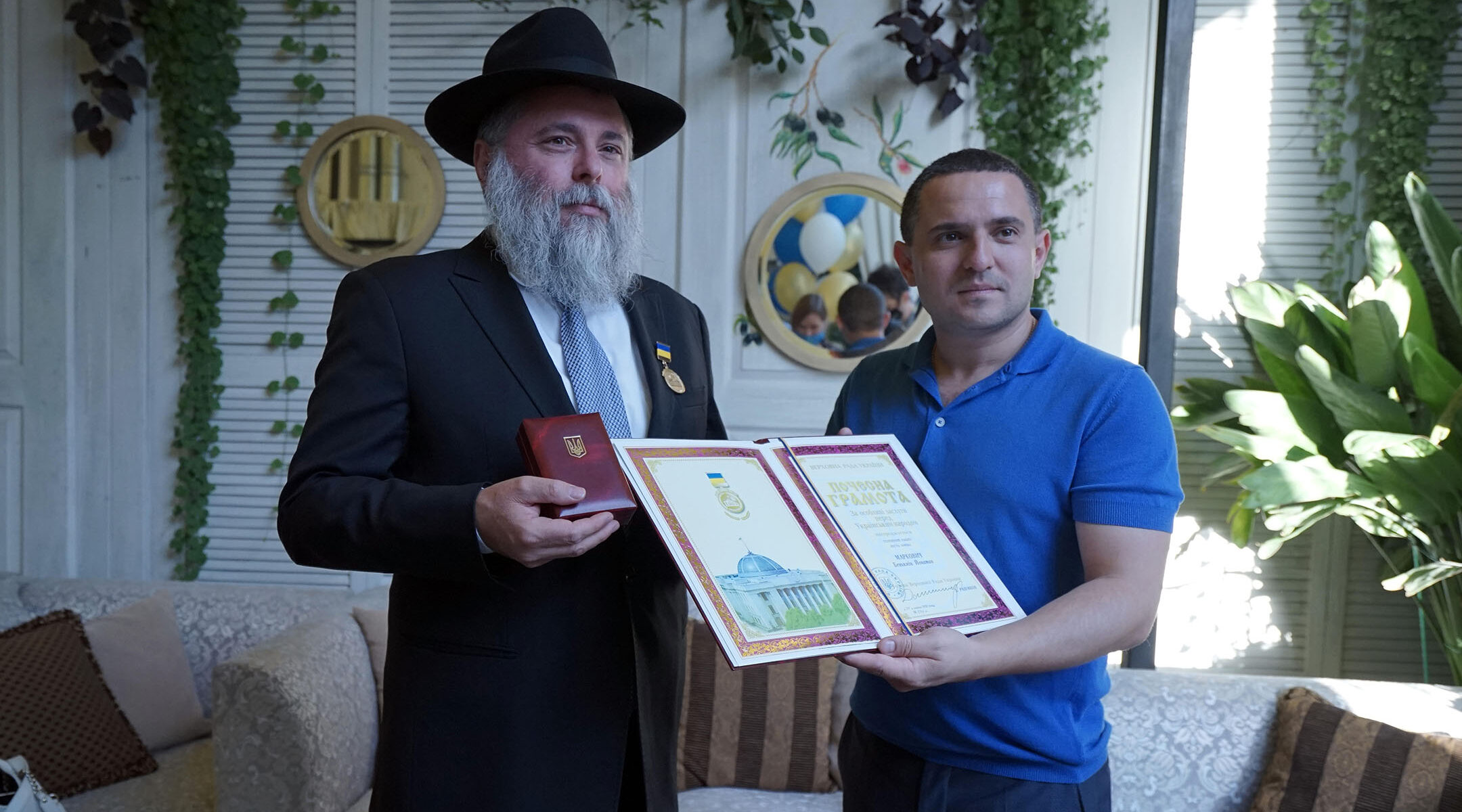 Rabbi Yonatan Markovitch, left, holds up a medal and a certificate he received at the parliament of Ukraine in Kyiv on Sept. 7, 2020. (Courtesy of Markovitch)