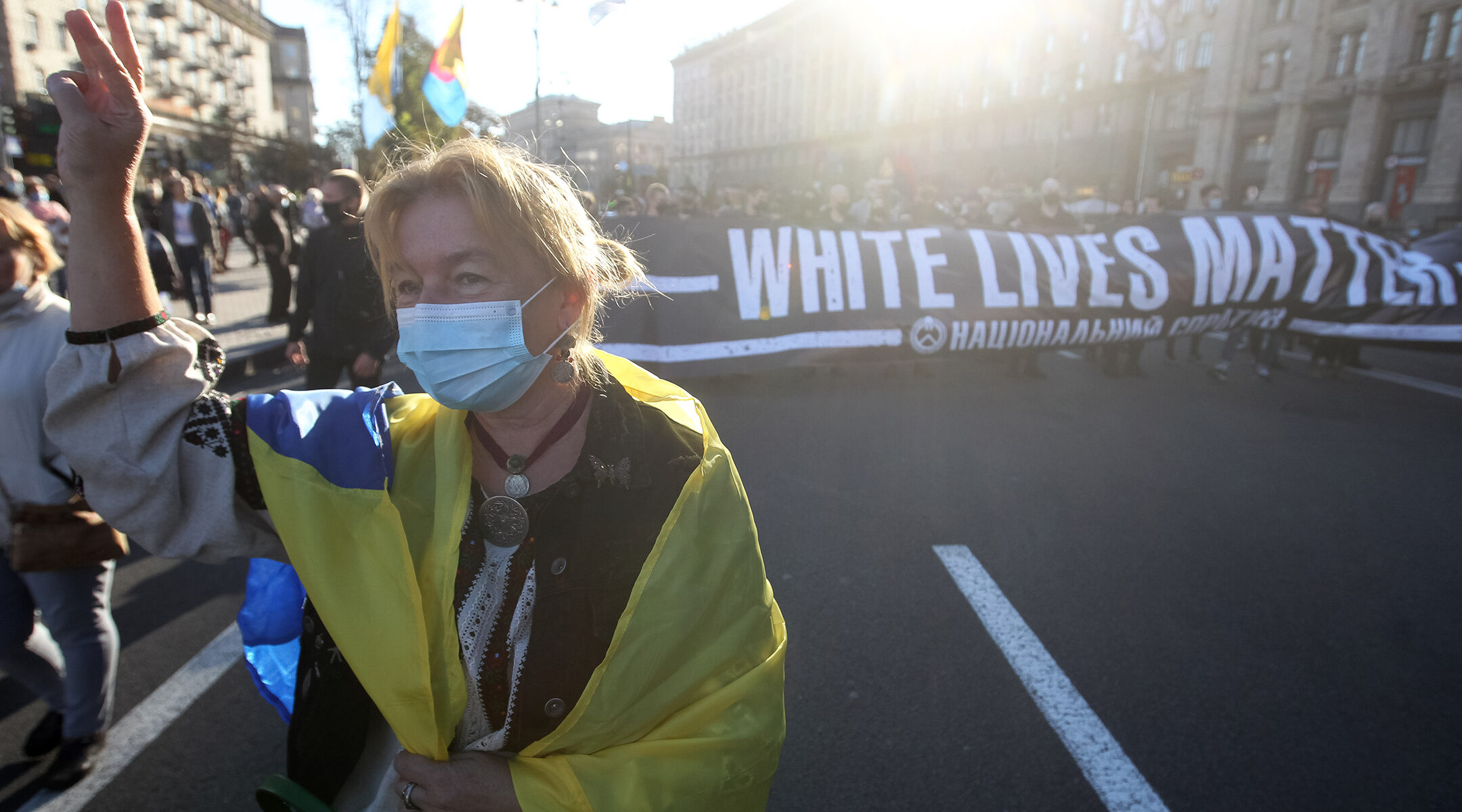 A woman wearing a Ukrainian flag performs an ultranationalist gesture while marching at an event honoring collaborators with Nazi Germany in Kyiv, Ukraine on Oct. 14, 2020. (STR/NurPhoto via Getty Images)
