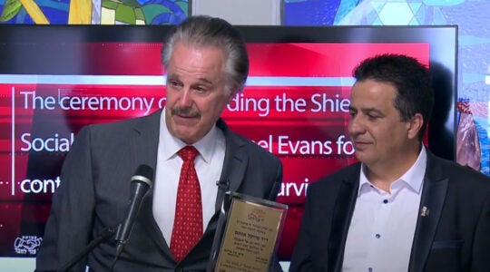 Mike Evans, left, receiving an award from Shimon Sabag, founder of Yad Ezer Lahaver, for his help in inaugurating a home for Holocaust survivors in Jerusalem, Israel on June 6, 2017. (Courtesy of Yad Ezer Lahaver)