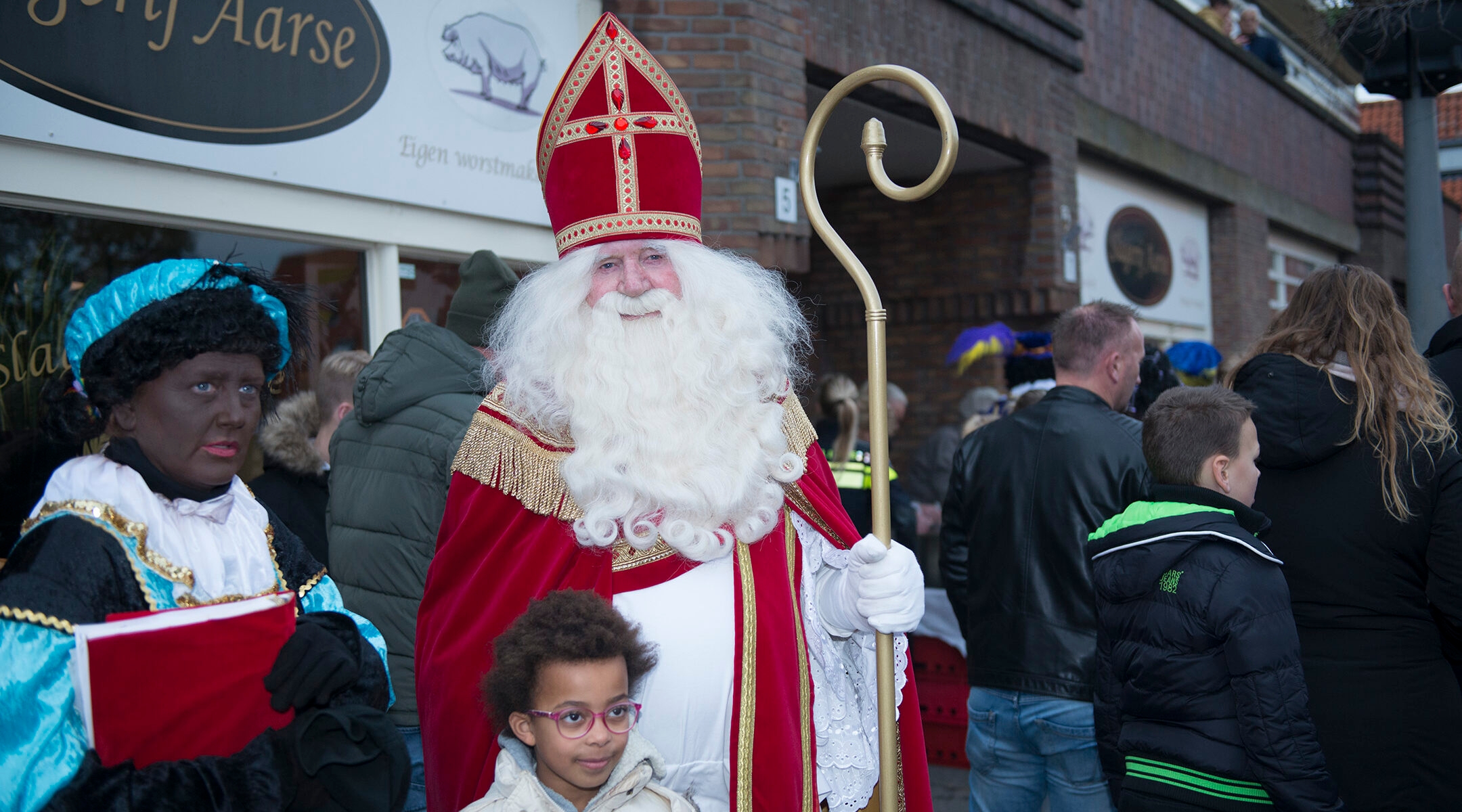 A child poses for a photo with a woman dressed as Black Pete and a man portraying Saint Nicholas in northern Amsterdam, the Netherlands on Nov. 16, 2019. (Cnaan Liphshiz)