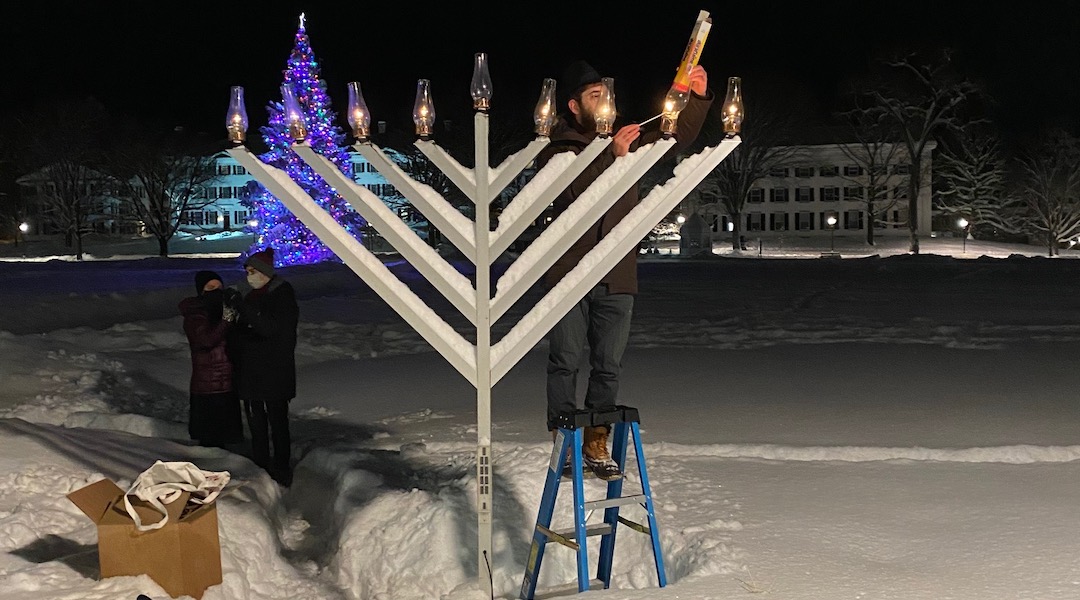Rabbi Moshe Gray lights the Dartmouth campus menorah the night after he discovered that it had been shot through with a pellet gun. The menorah can still be lit with fire despite the vandalism. (Courtesy of Gray)