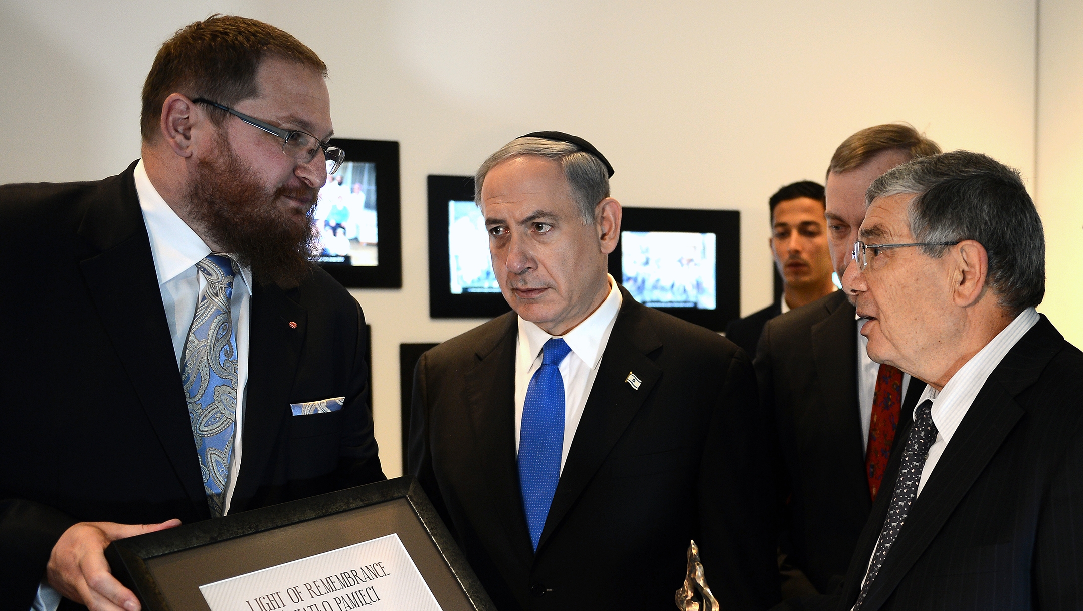 Piotr Cywinski, left, confers on Yad Vashem Chairman Avner Shalev, right, an award during visit by Israeli Prime Minister Benjamin Netanyahu, center, at the former Nazi death camp Auschwitz-Birkenau State Museum Poland on June 13, 2013. (Janek Skarzynski/AFP via Getty Images)