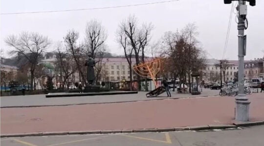 A man topples a Hanukkah menora in Kyiv, Ukraine on Dec. 10, 2020. (ZIK)