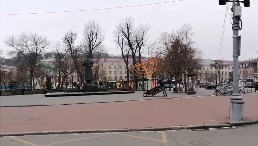 A man topples a Hanukkah menora in Kyiv, Ukraine on Dec. 10, 2020. (ZIK)