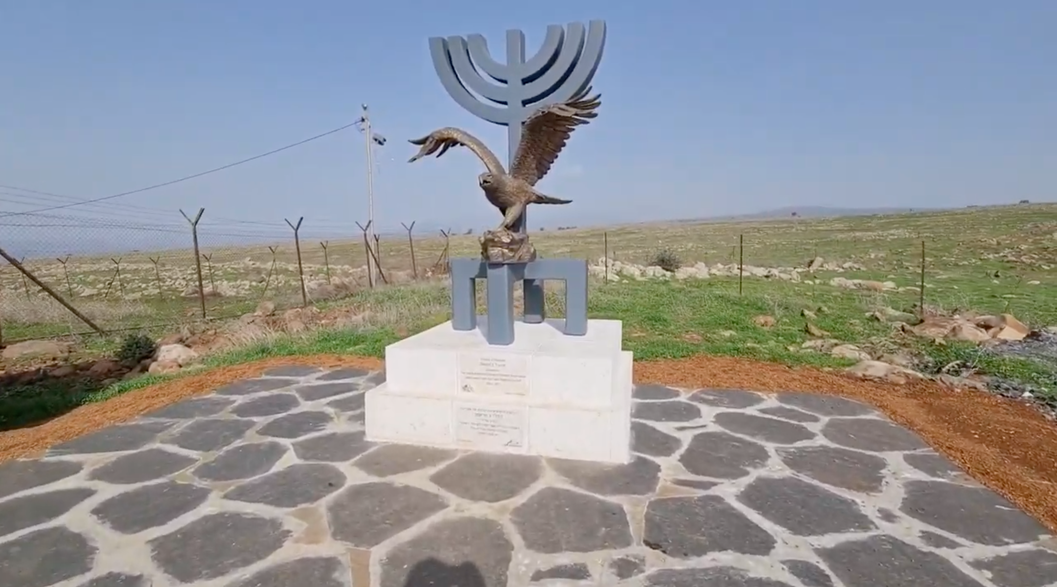 Next to the large sign bearing the town's name is a monument with a plaque honoring Trump. (Screenshot from YouTube)