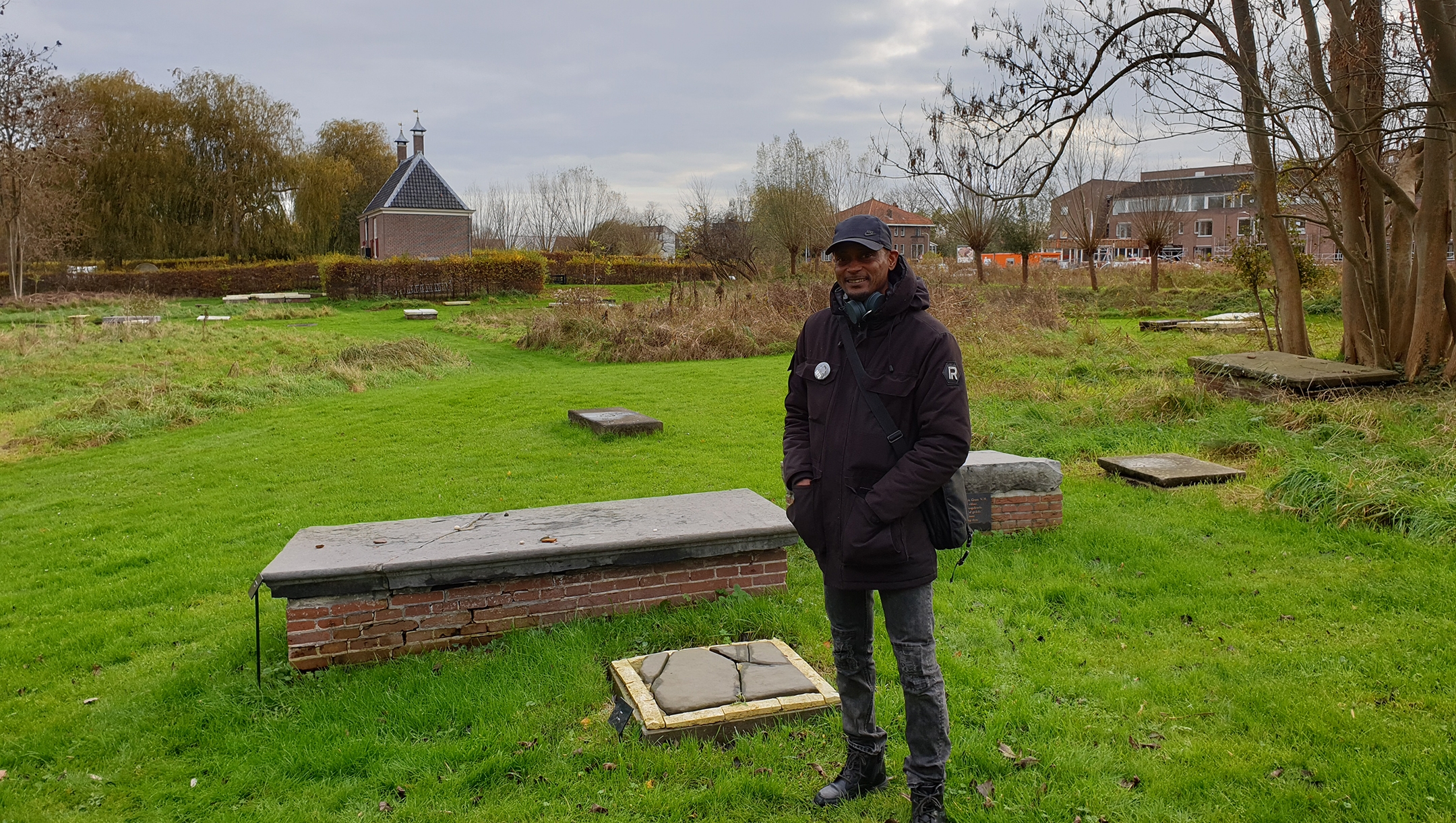 Sergio Berrenstein stands next to the grave of Elieser and his master at the entrance to the Jewish cemetery in Ouderkerk aan de Amstel, the Netherlands on Nov. 20, 2020. (Cnaan Liphshiz)