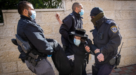 Police officers carry a protester away during raid on a Jerusalem yeshiva that remained open in violation of COVID-19 restrictions on January 19, 2021. (Yonatan Sindel/Flash90)