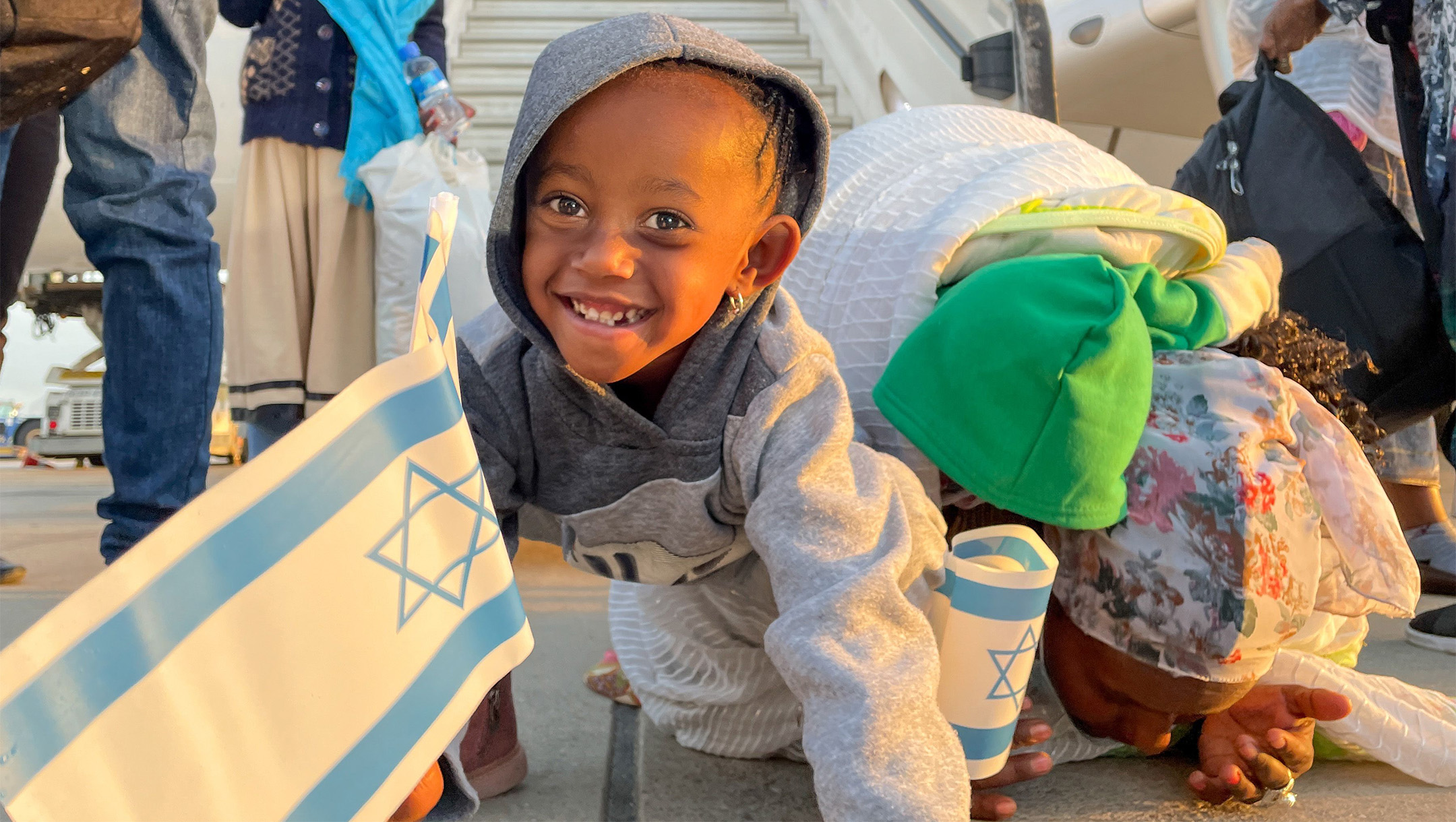 A girl smiles upon arriving from Ethiopia as her mother kisses the ground at Ben Gurion Airport in Israel on Feb. 12, 2021. (Courtesy of ICEJ)