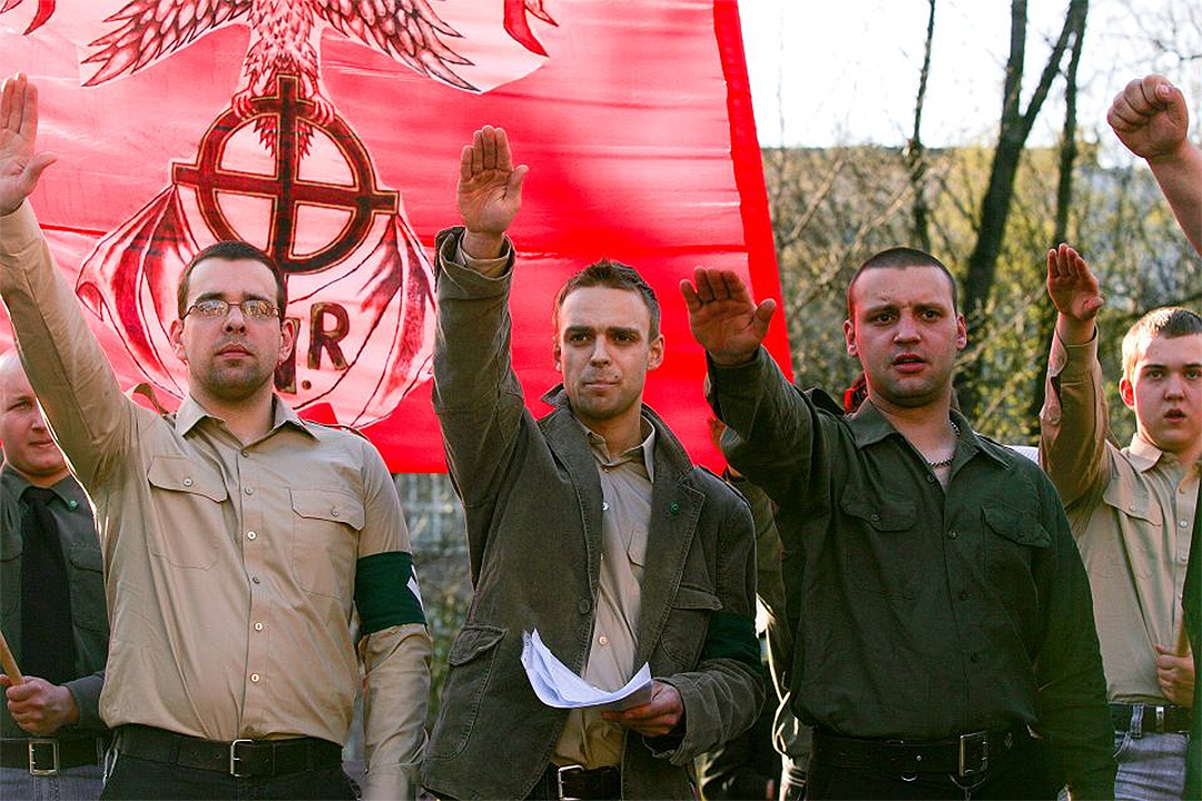 Tomasz Greniuch, holding papers, makes a gesture that appears to be a Nazi salute at a far-right event in Poland in 2007. (Bartosz Siedlik, courtesy of Gazeta Wyborcza)