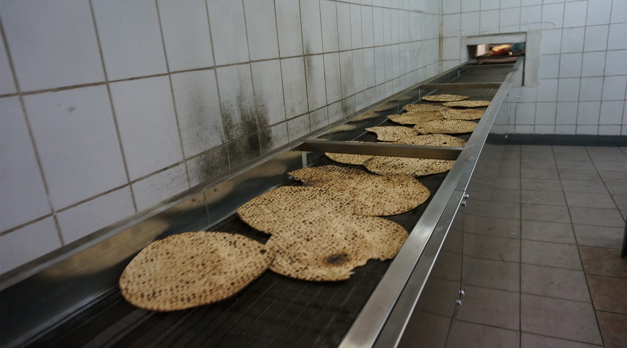 Matzahs travel on the production line of the Tiferet HaMatzot factory in Dnepro, Ukraine on Dec. 8, 2014. (Cnaan Liphshiz/JTA)