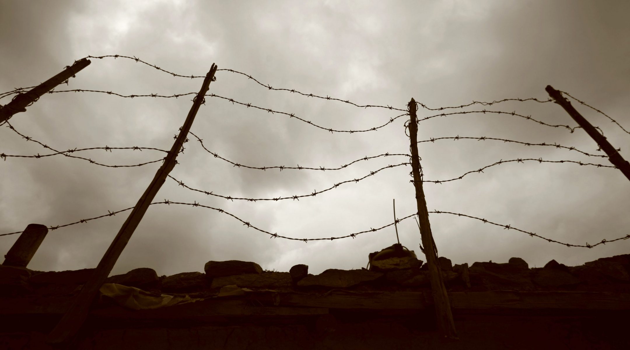 Barbed wire fence against a dark sky