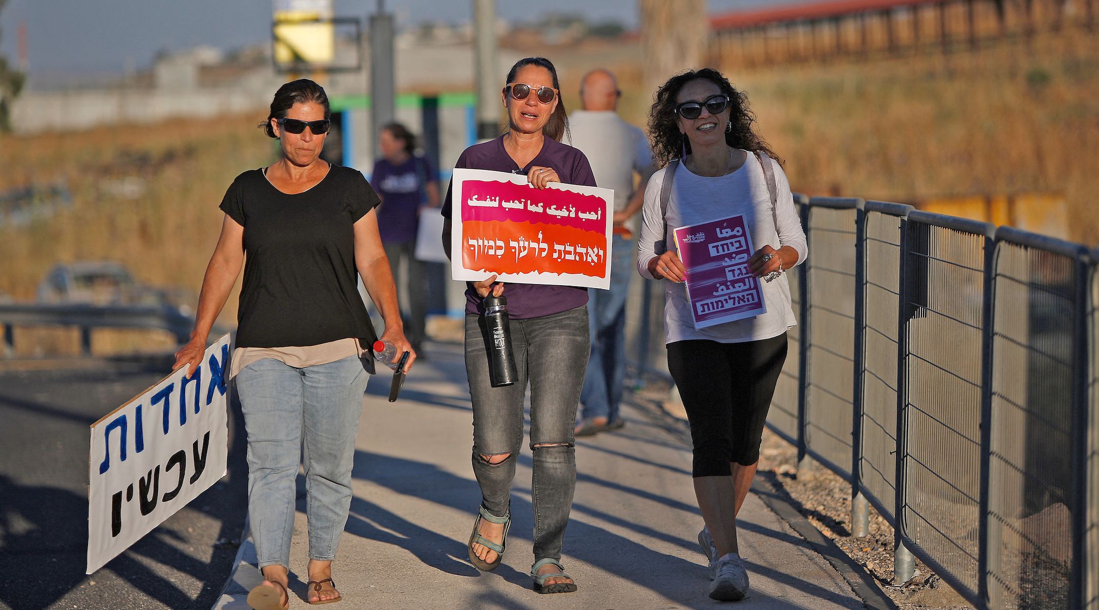 Three women walk in a demonstration for coexistence in northern Israel on May 11, 2021. The sign in the middle says "Love your neighbor as yourself." (Jalaa Marey/AFP)