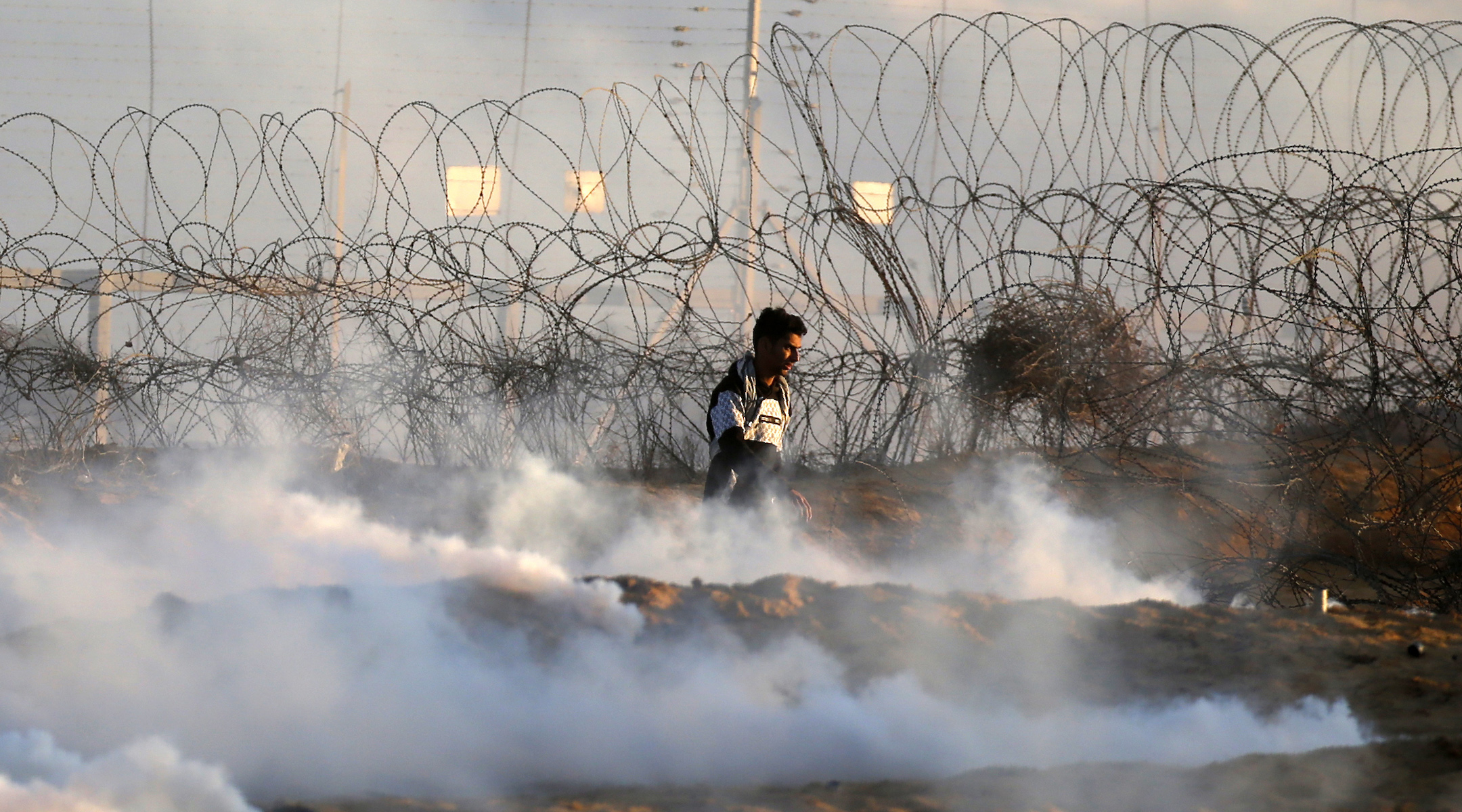 A Palestinian demonstrator walks amidst tear gas smoke fired by Israeli forces during a protest near the Israel-Gaza border fence in the southern Gaza Strip, on December 27, 2019. (Said Khatib/AFP via Getty Images)