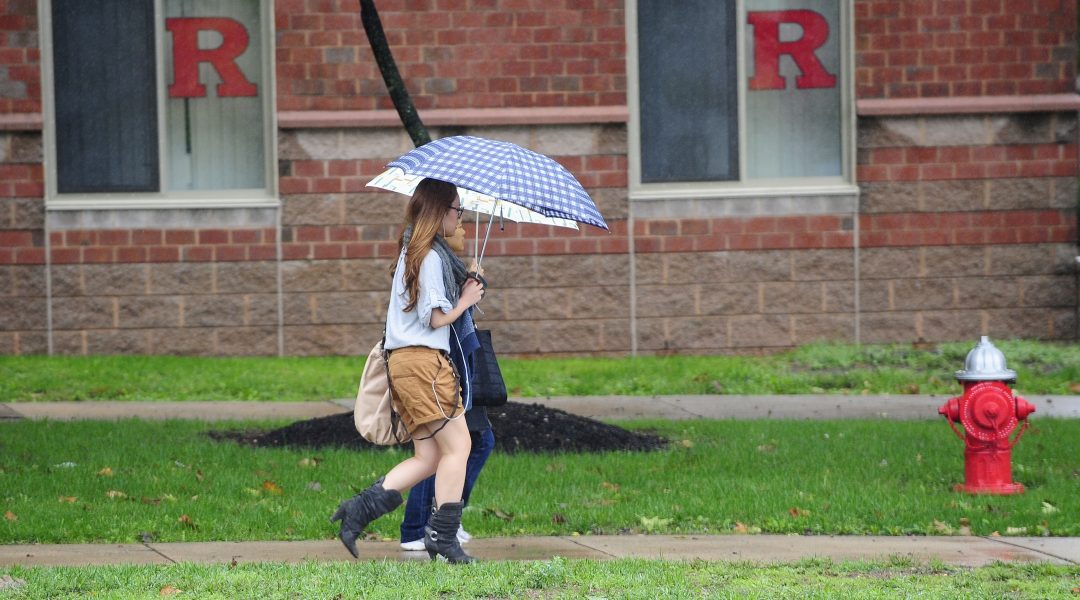 A student holds an umbrella outside a Rutgers dormitory