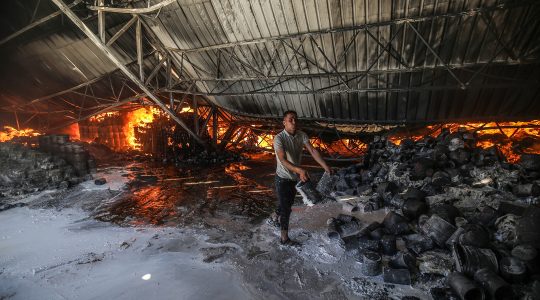 Firefighters attempt to extinguish a fire at a warehouse which was hit during an Israeli airstrike in Rafah, in the southern Gaza Strip, on May 18, 2021. (Abed Rahim Khatib/Flash90)