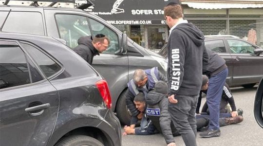 Men from the CST and Shomrim security units detaining a man whom witnesses said assaulted a Jewish man in a car in London, the UK on May 21, 2021. (Eye on Antisemitism)