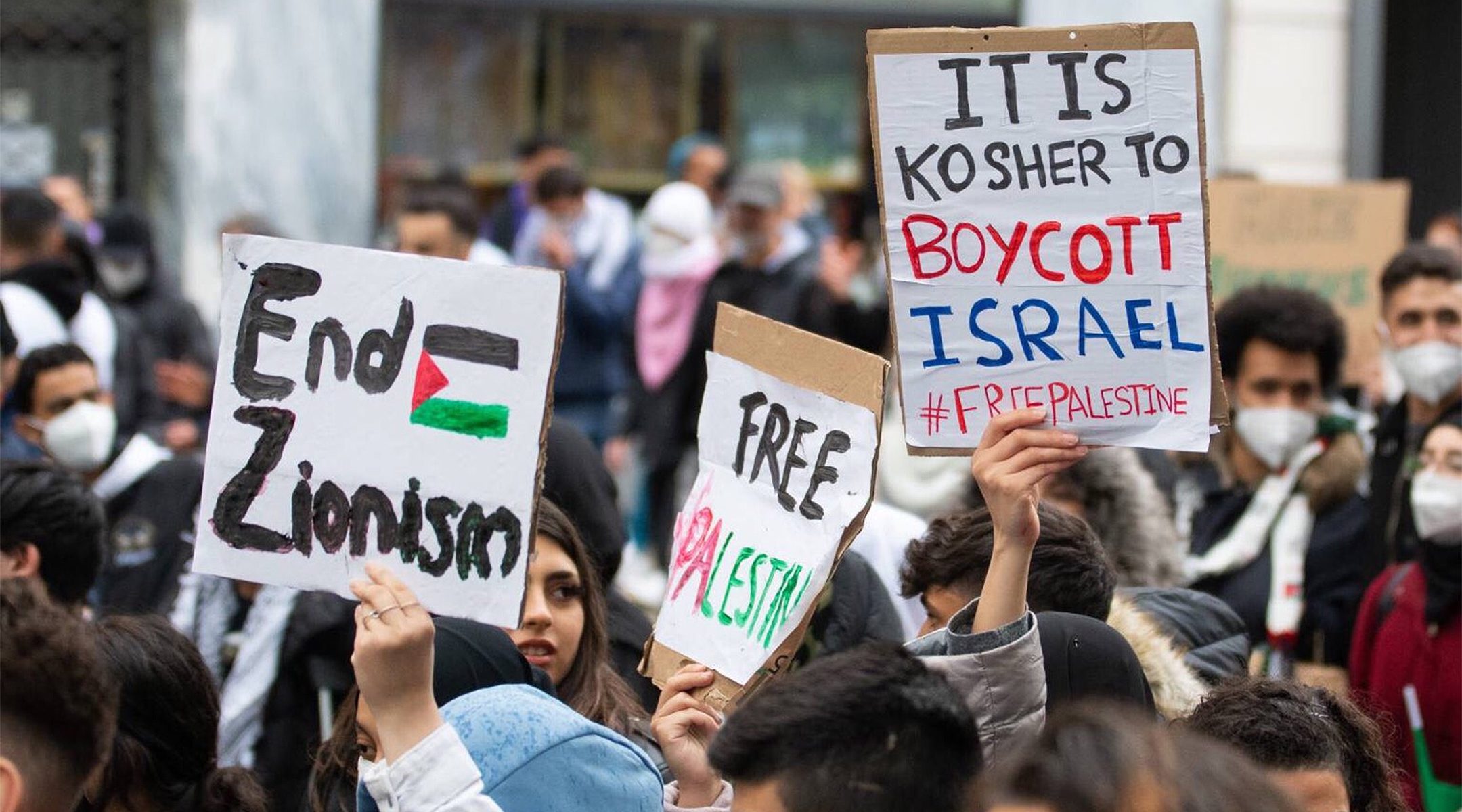 Demonstrators against Israel hold up signs at a rally in Vienna, Austria where protesters chanted in Arabic about a massacre of Jews on May 13, 2021. (Courtesy of Austrian Union of Jewish Students)