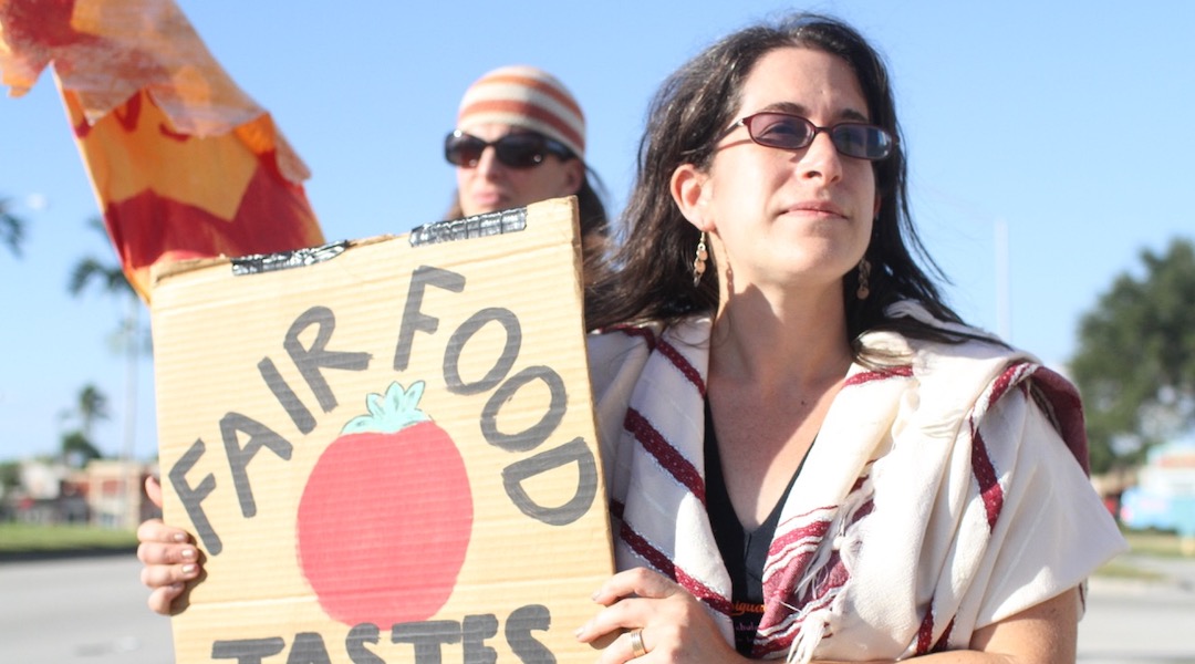 Rabbi Rachel Kahn-Troster holding a sign at a protest