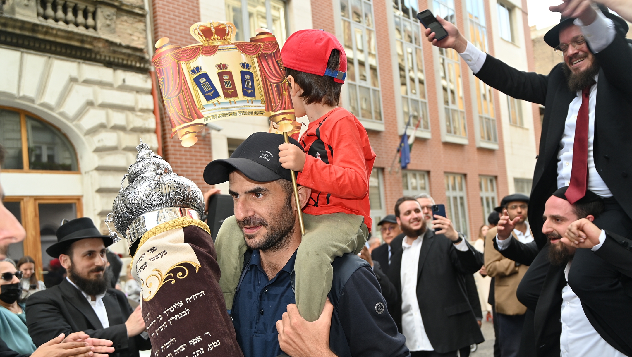 A father carries a Torah scroll into the Vorosmarty Street Synagogue in Budapest, Hungary on Aug. 27, 2021. (Cnaan Liphshiz)