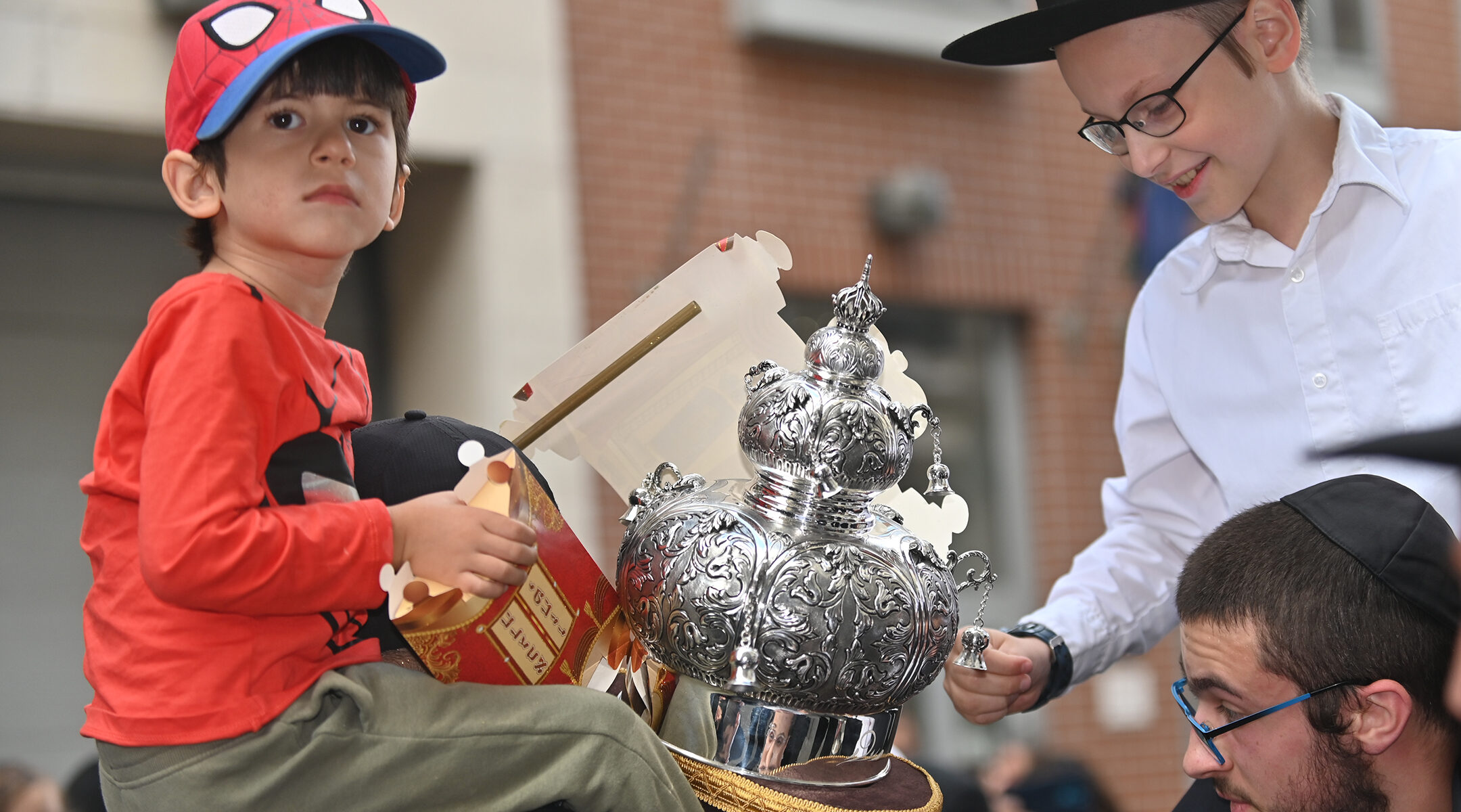 Children examine a Torah scroll as it is being carried into the Vorosmarty Street Synagogue in Budapest, Hungary on Aug. 27, 2021. (Cnaan Liphshiz)