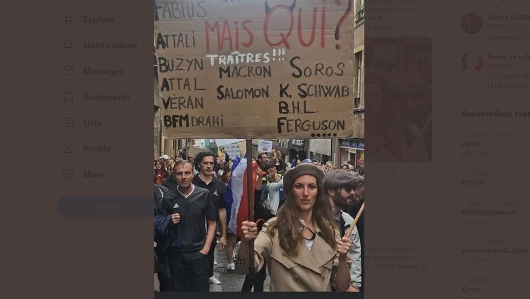 A woman holds up a placard denouncing President Emmanuel Macron and several prominent Jews denounced as traitors at a protest against COVID restrictions in Metz, France on Aug. 7, 2021. (Gérald Darmanin/Twitter)