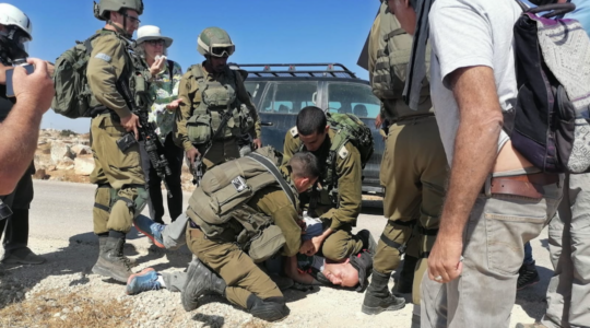 soldier kneels on the neck of an activist