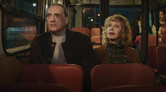A middle-aged couple on a bus in Israel in a movie still.