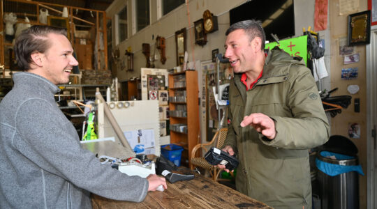 Gideon Italiaander, right, bargains with a customer at his shop in Amsterdam, the Netherlands on Oct. 11, 2021. (Cnaan Liphshiz)