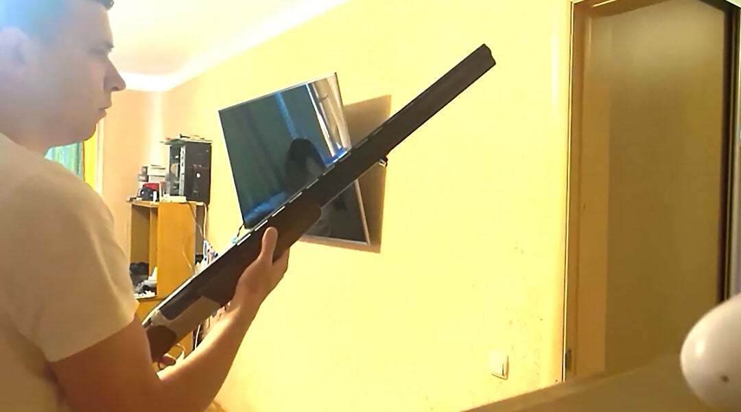 Andrei Zeltzer stands with a hunting rifle behind the door of his home in Minsk, Belarus on Sept. 29, 2021. (Maria Uspenskaya)