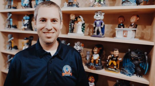 Phil Sklar posing in front of bobbleheads