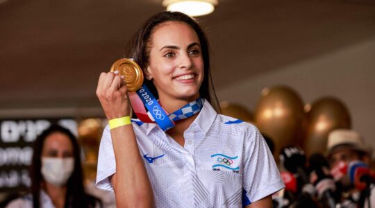 Linoy Ashram poses with her gold medal upon arrival from Tokyo at Ben Gurion International Airport