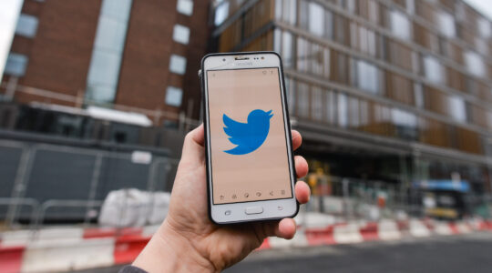 Twitter logo on a phone in front of a building