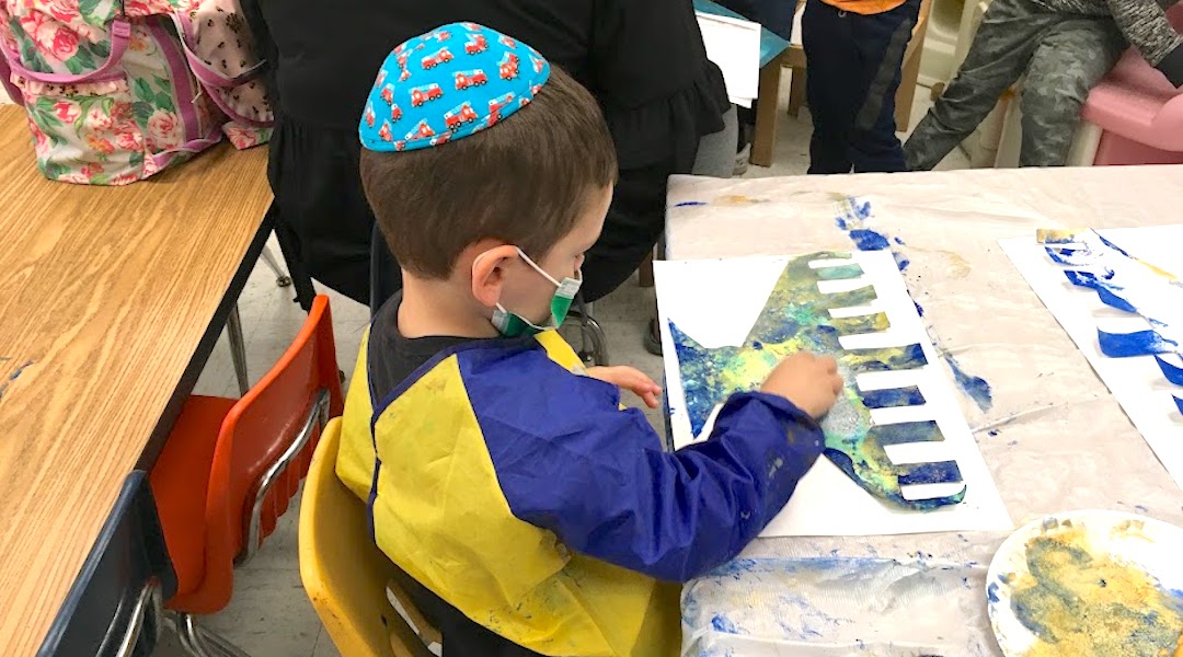 Kid paints a Hanukkah menorah