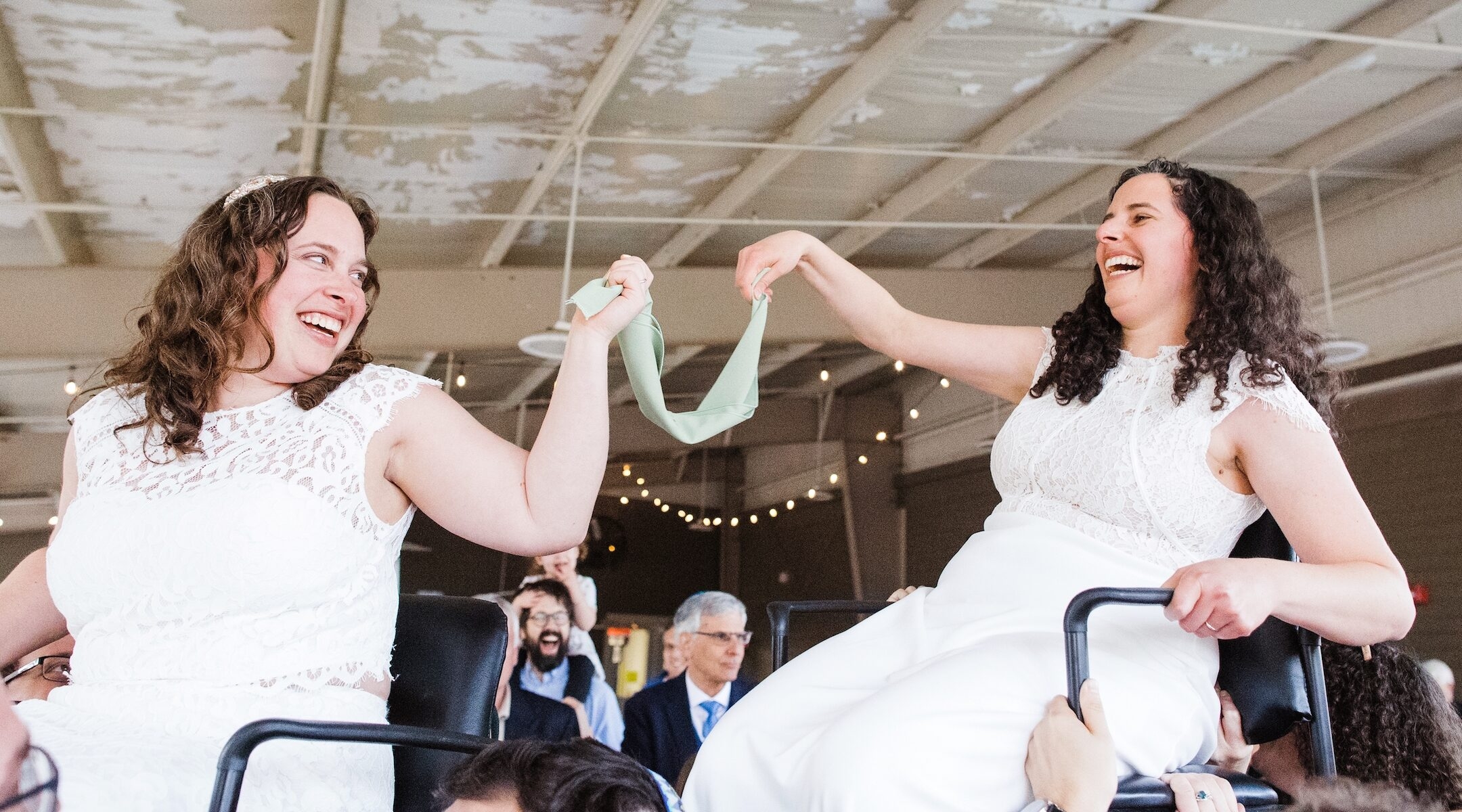 Two brides being lifted during the hora at a Jewish wedding