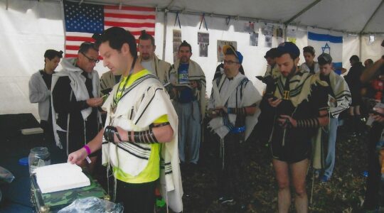 Runners in tallit and tefilin pray before their race.
