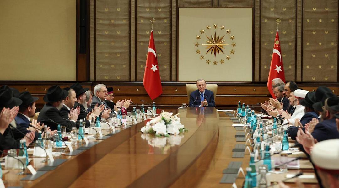 A group of men around a conference table adorned with Turkish flags