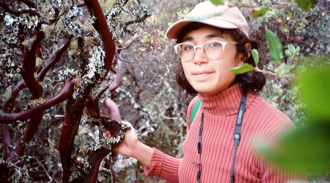 An artist poses by a tree