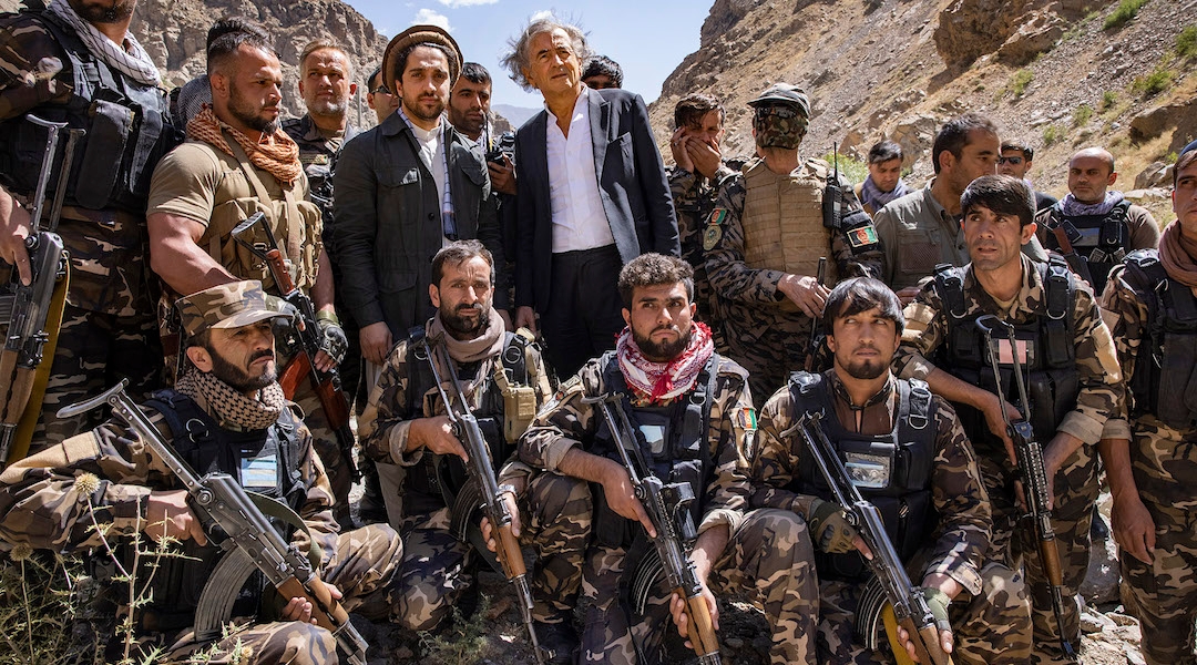 A suited man standing in a group of armed militias