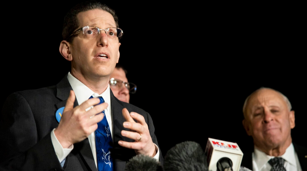 A man speaking in front of microphones